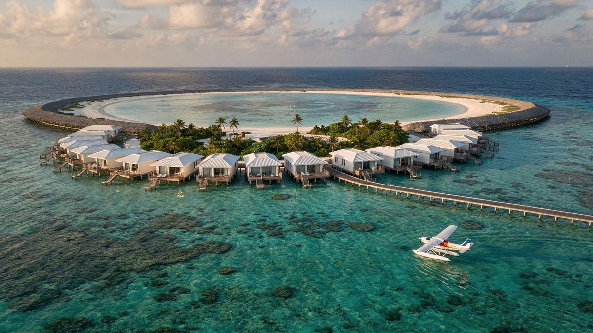 Aerial view of an atoll lagoon with overwater villas and a seaplane on the water